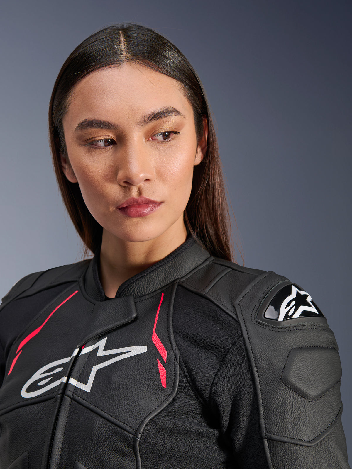 Kvinde iført Alpinestars Stella Dusk læderjakke i Black Diva Pink White, med hvidt brystlogo, livlige lyserøde detaljer og ekstern DFS-skulderbeskyttelse, førsteklasses motorcykeludstyr i bovint læder