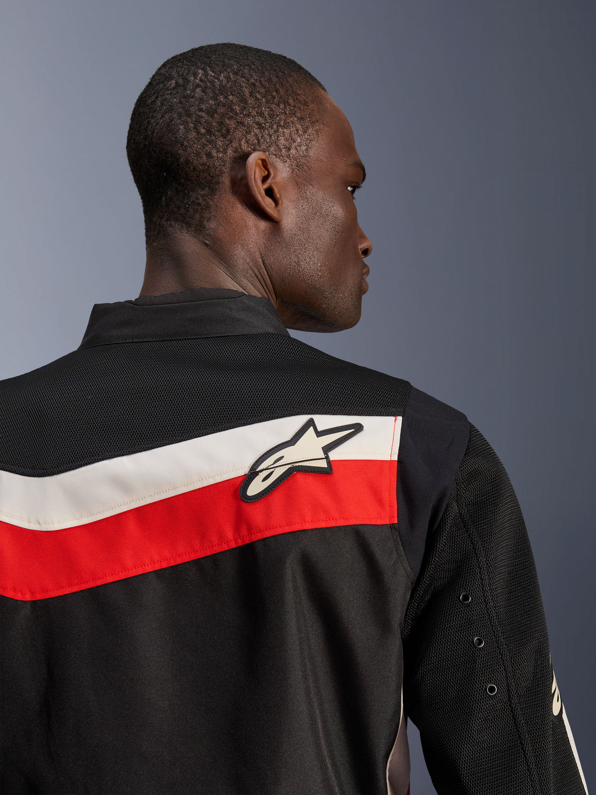 Alpinestars T-Dyno Air Jakke, sort, klar rød og ecru, nærbillede af øverste del af ryg og skulder, med vandrette røde og ecru-farvede striber og et hvidt Astars-logo, åndbare 3D-mesh-paneler på bærestykket og ærmerne, moderne klassisk tekstil-motorcykeljakke