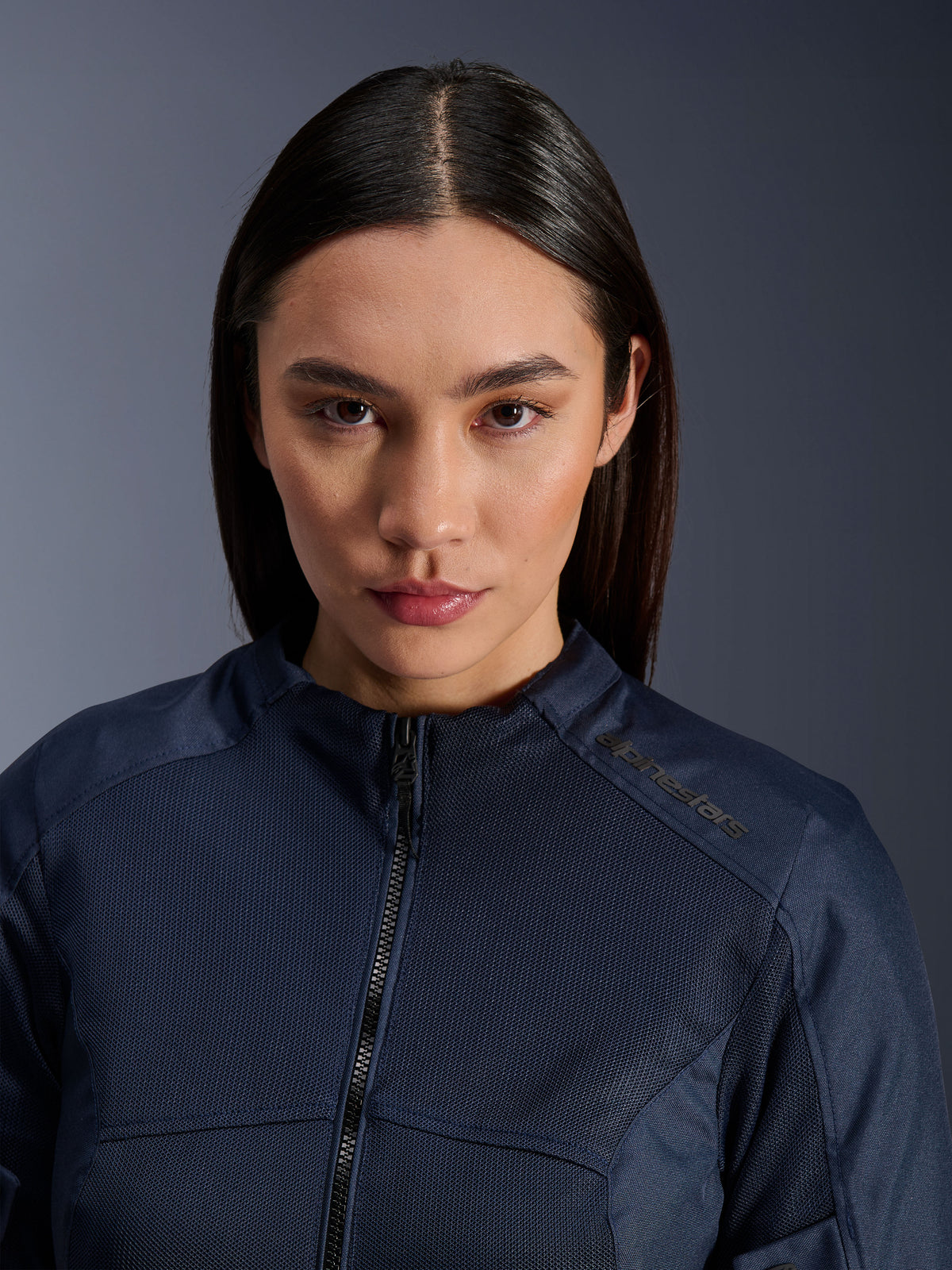 Kvindelig model iført Alpinestars Stella C-1 Air-jakken i mørkeblå, nærbillede med fokus på åndbar mesh-tekstur, lynlås foran og Alpinestars-logo på kraven, stilfuldt urbant motorcykeltøj