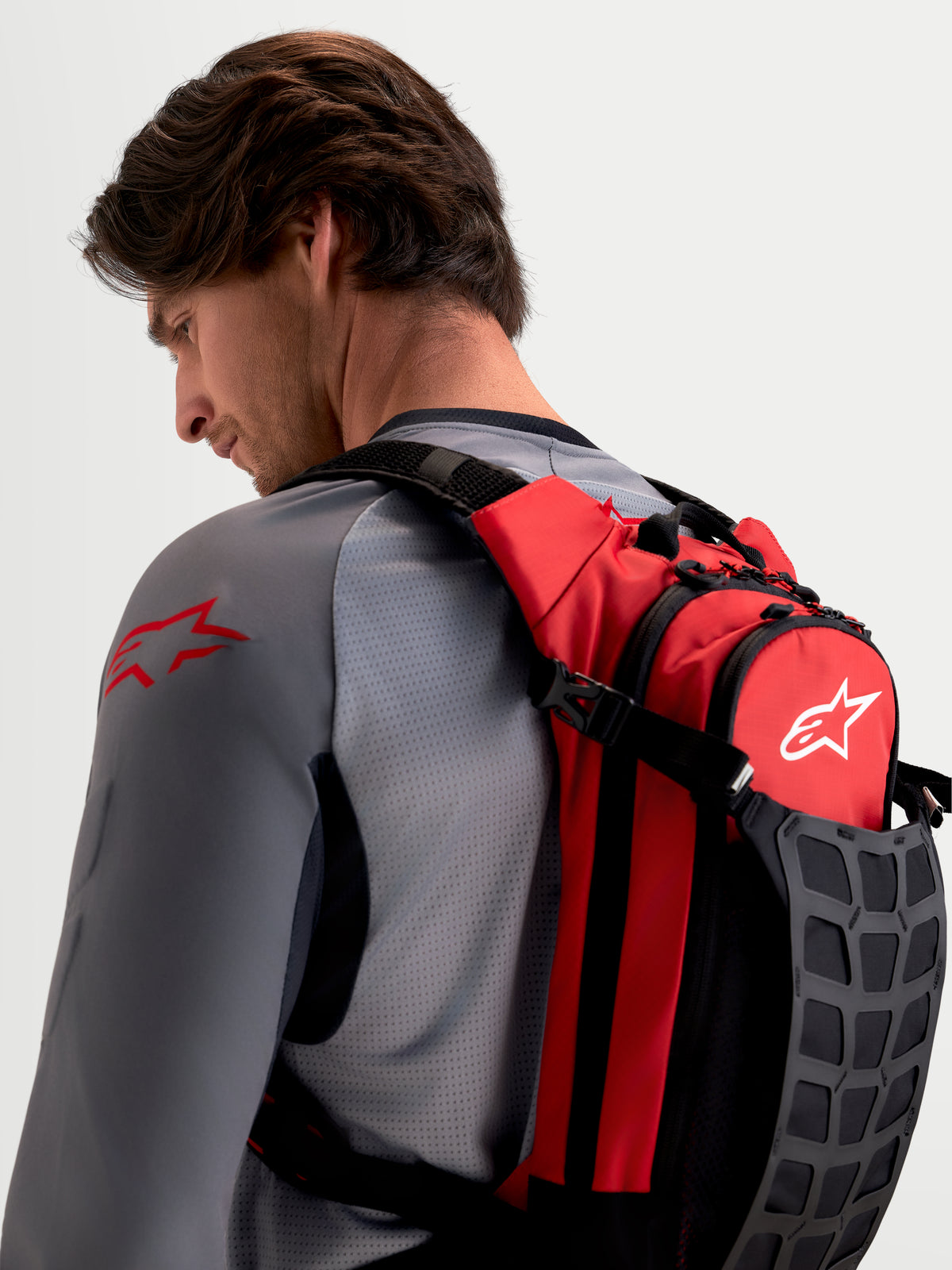 Alpinestars AT-9 rygsæk, motocrossrygsæk i rød og sort, båret af mandlig model med polstrede skulderstropper og organiseret opbevaring til baneudstyr
