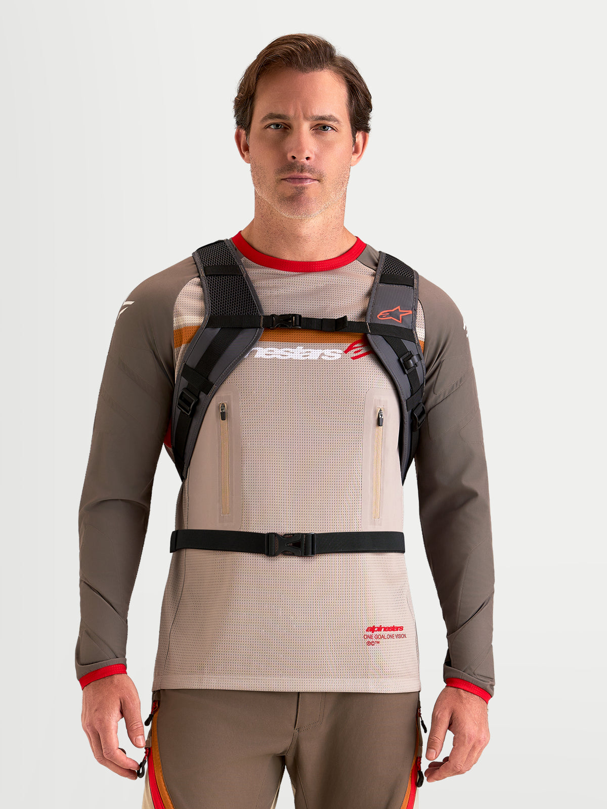 Alpinestars AT-9 Backpack, motocross backpack in walnut and deep gray, front view on a model wearing padded shoulder harness and buckled strap system