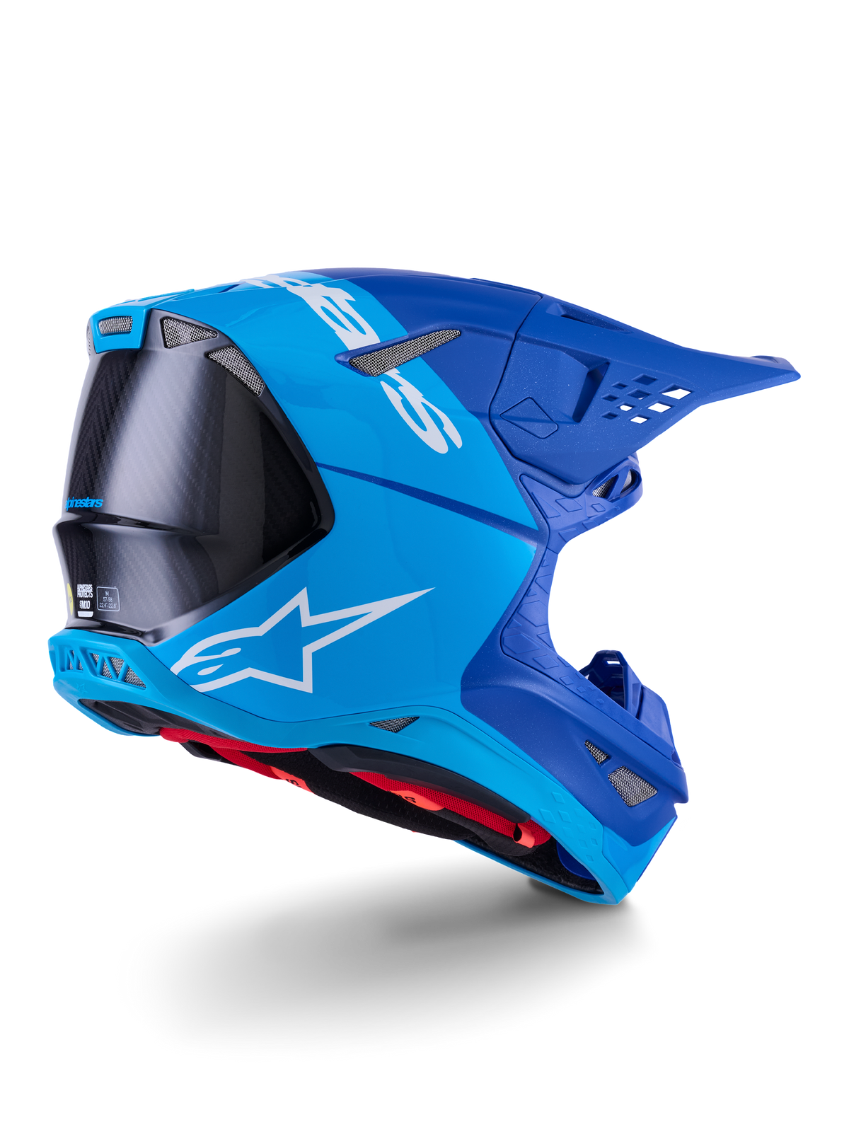 Alpinestars Supertech M10 Flood-hjelm, motocross-hjelm, lyseblå og navyblå med synlig sort kulfiber, profil fra bagside og side, der viser ventilationsporte og hvidt logo, rødt indvendigt for, avanceret aerodynamisk design til terrænkørsel