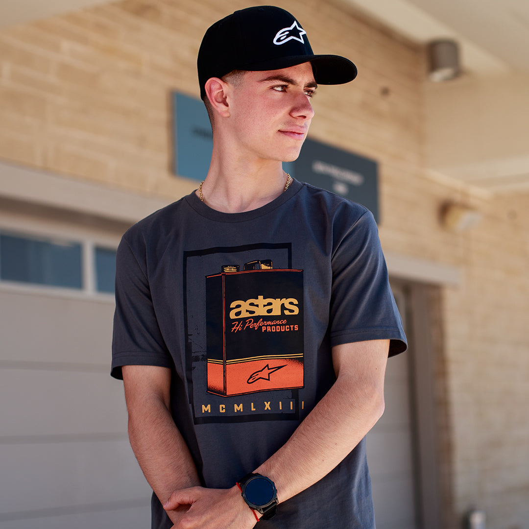 Alpinestars Galun CSF Tee, Short Sleeve T-Shirt, Charcoal, front vintage gas can graphic with 'astars' branding and 'MCMLXIII' Roman numerals, worn by a man with a black logo cap, casual motorsport lifestyle