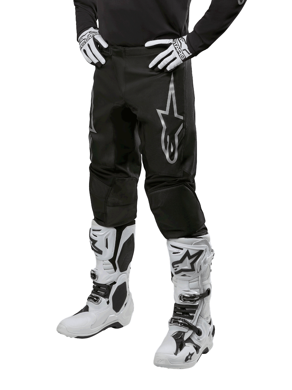 Alpinestars 2024 Fluid Graphite Pants, Motocross Pants, Black and Silver, featuring a silver Alpinestars logo on the thigh, shown worn with white motocross boots and gloves, designed for off-road motorcycle racing