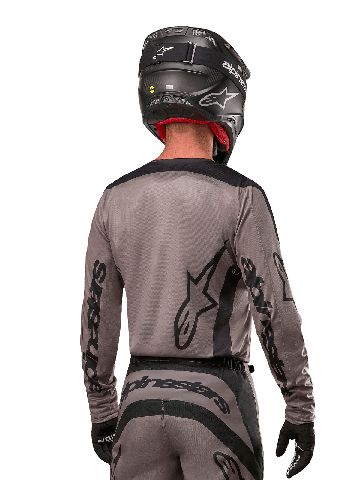 Alpinestars 2024 Fluid Lurv Jersey i Mud Black, motocrossrytter set bagfra, sort Alpinestars-branding på ærmer og ryg, sort hjelm og matchende udstyr til off-road racing