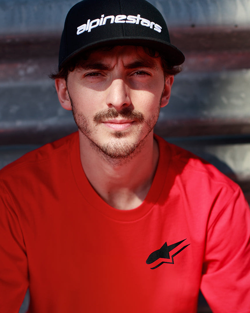 Alpinestars Formulate Csf Tee i rød, Francesco Bagnaia iført kortærmet t-shirt med sort Astars-logo og sort kasket, afslappet motorsport-streetwear