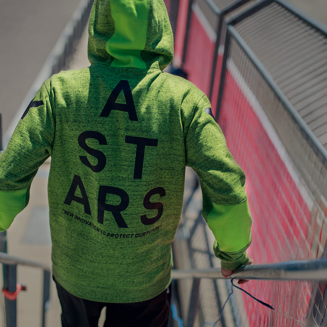 Alpinestars Perpetuate hættetrøje, set bagfra, limegrøn meleret fleece, stor sort ASTARS-tekstgrafik på ryggen, afslappet sportstøj med stofblokering og hætte med snøre