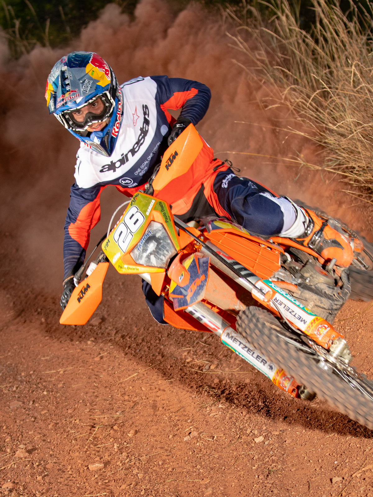 Enduro-kører i aktion på en orange motocrosscykel, iført Alpinestars Pro-Dura Jersey i Navy, Hot Orange og hvid, med et let og åndbart design og markant branding til off-road-performance.
