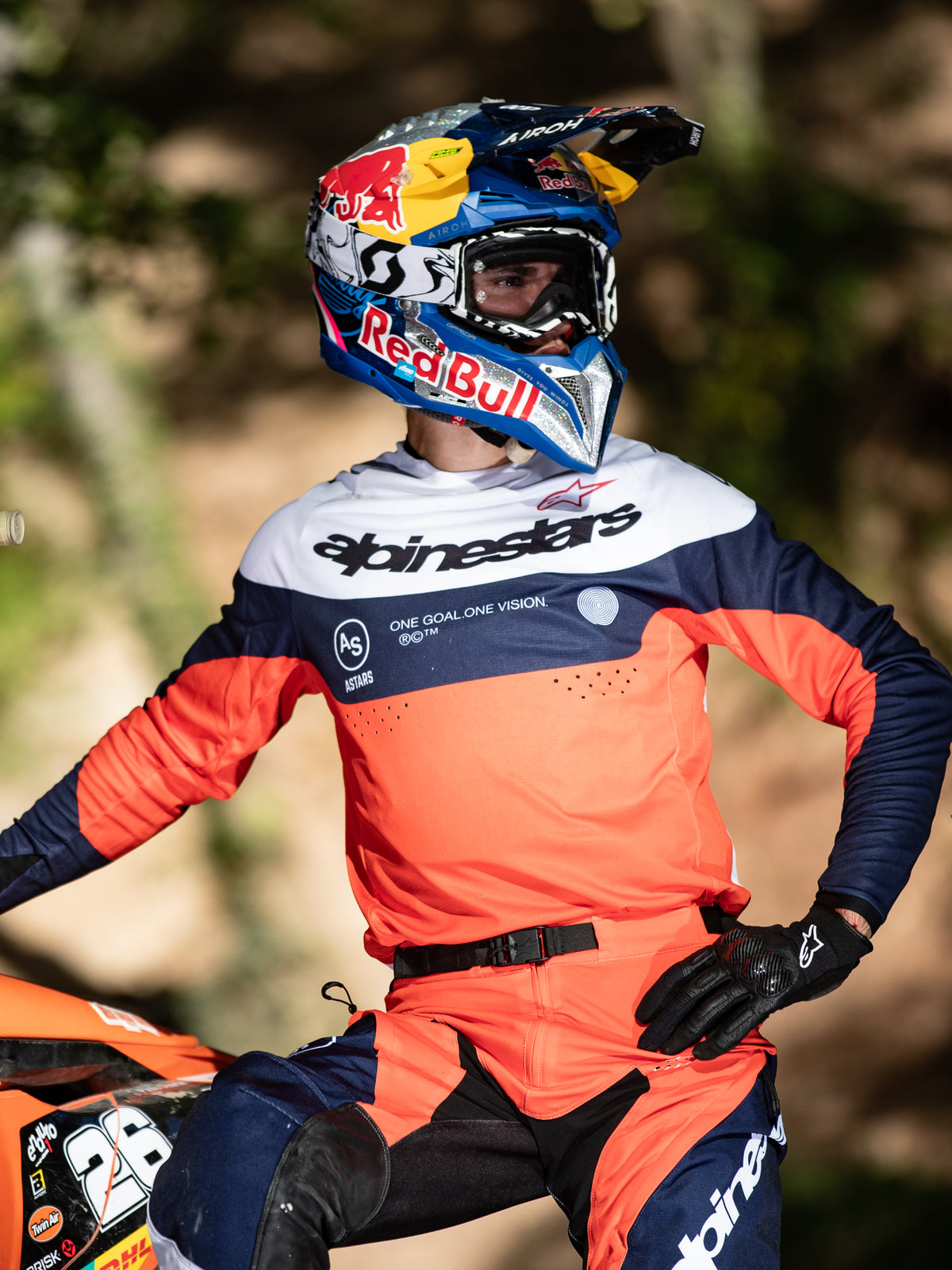 Motocross-kører iført Alpinestars Pro-Dura Jersey i navyblå, Hot Orange og hvid, med markant branding på brystet og laserperforeringer, kombineret med en Red Bull-racerhjelm, professionelt udstyr til enduro- og terrænkørsel.