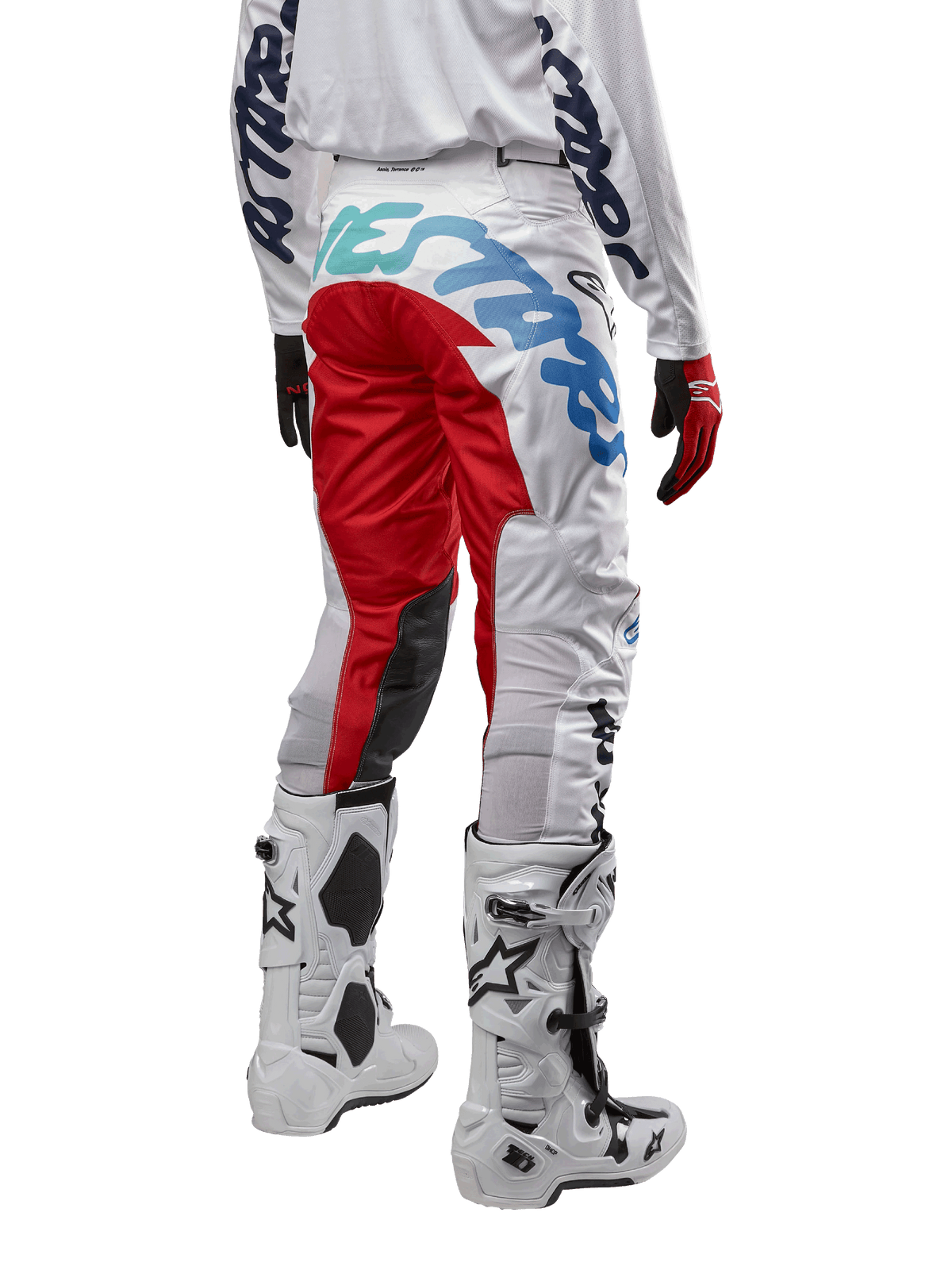Alpinestars 2024 Racer Hana bukser, motocrossbukser, hvid flerfarvet med røde og blå accenter, set bagfra med stort branding på sædet, båret med hvide og sorte motocrossstøvler, designet til off-road ydeevne og holdbarhed