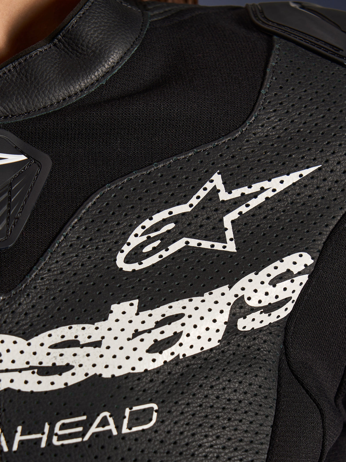 Nærbillede af Alpinestars Stella GP-R7 2-delt læderdragt i sort, med perforerede læderpaneler, et stort hvidt Alpinestars-logo på brystet og åndbare sektioner i strækstof.