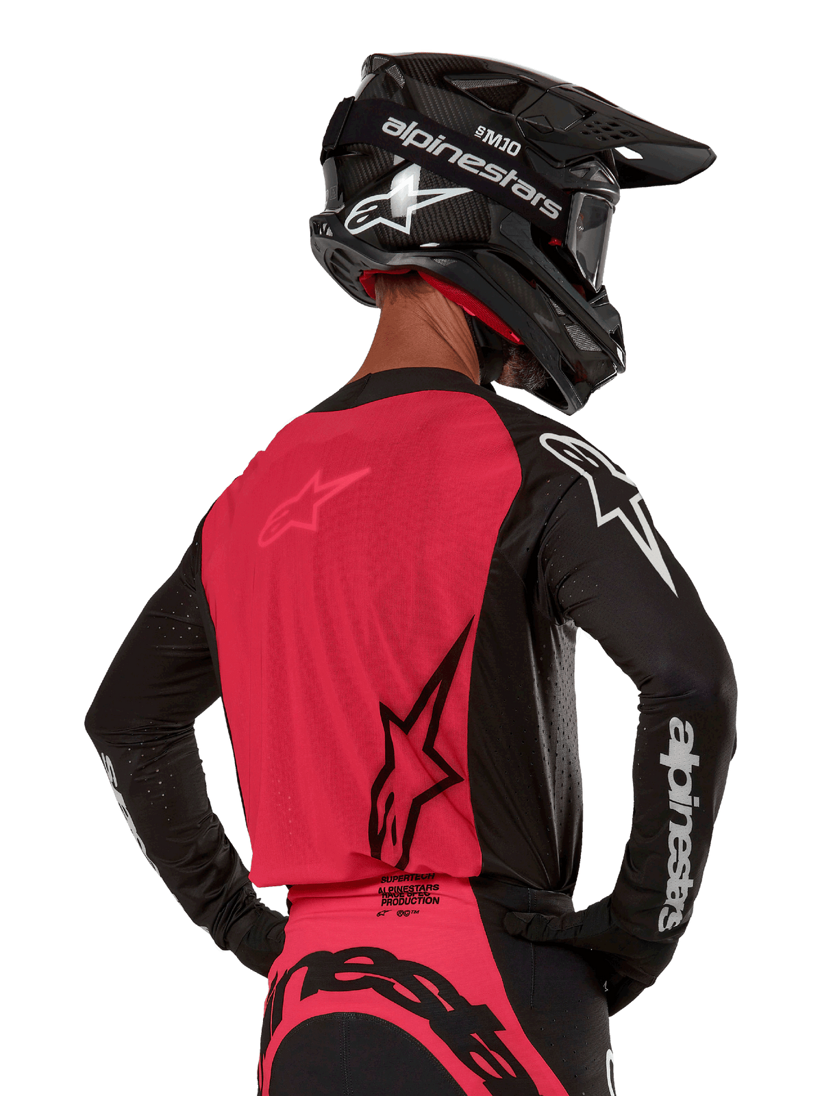 Alpinestars 2024 Supertech Ward Jersey, Motocross Jersey, Black and Red Berry, back view showing red mesh panel and black sleeves with white branding, worn with a black carbon fiber helmet and gloves, athletic race fit for off-road riding