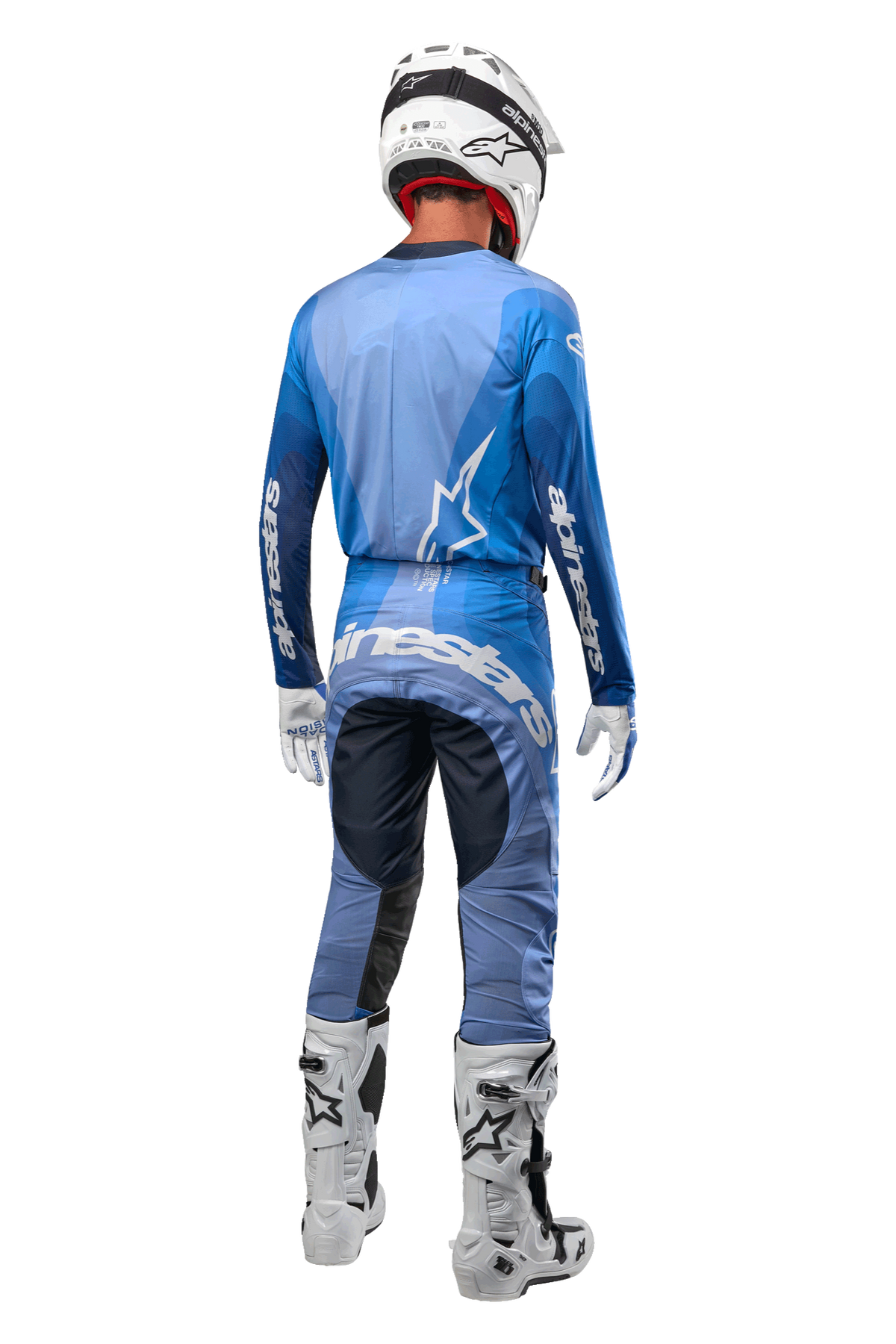 Motocross rider from behind wearing Alpinestars 2024 Techstar Pneuma Pants in Dark Navy and Light Blue, coordinated with a matching blue jersey, white helmet, white gloves, and white boots, featuring bold Alpinestars branding across the seat and sleeves.