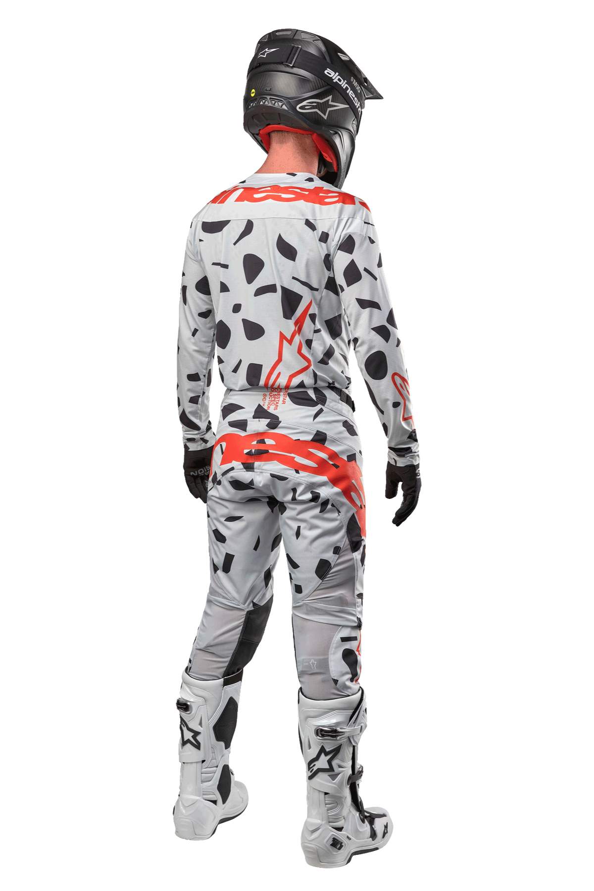 Motocrosskører set bagfra iført Alpinestars 2024 Techstar Rantera bukser, Haze Gray Camo med sorte pletter og røde logoer, matchende trøje, sort hjelm og hvide støvler, komplet off-road racerudstyr