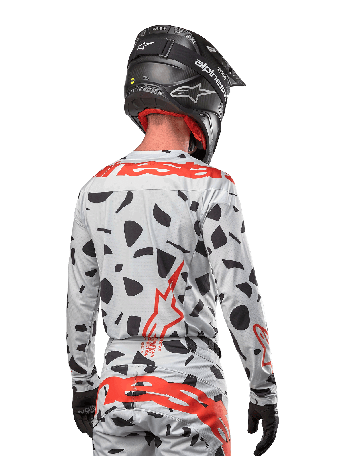 Motocrossrytter set bagfra iført Alpinestars 2024 Techstar Rantera Jersey i Haze Gray Camo, lysegrå base med sorte grafiske pletter og markante røde Alpinestars-logoer på ryggen og skuldrene, kombineret med matchende bukser og en sort hjelm.
