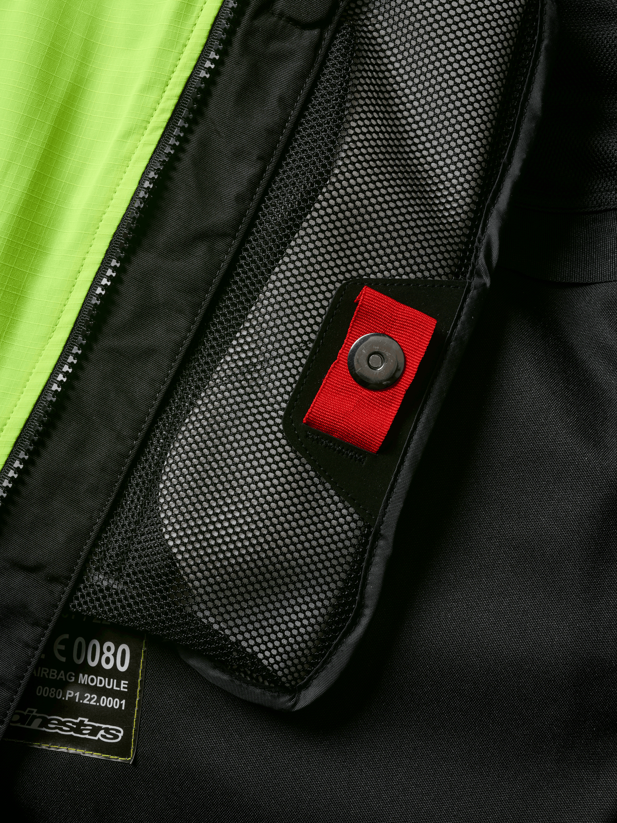 Alpinestars Tech-Air® 3 V2 System detalje, tætbillede af indvendig mesh-lomme med rød trækstrop og trykknap, stærk gul fluo-panel, sort tekstilkonstruktion med airbag-modul mærkat og lynlås