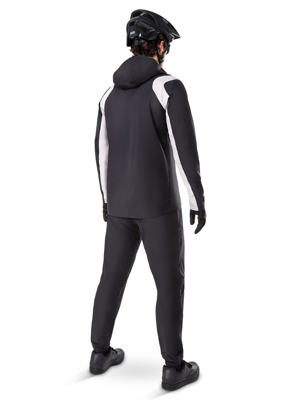 Alpinestars A-Dura Rain Jacket, set bagfra af en mandlig cyklist iført den sort-hvide vandtætte MTB-jakke, matchende sorte cykelbukser, sort hjelm og handsker, teknisk udstyr til mountainbike under våde forhold