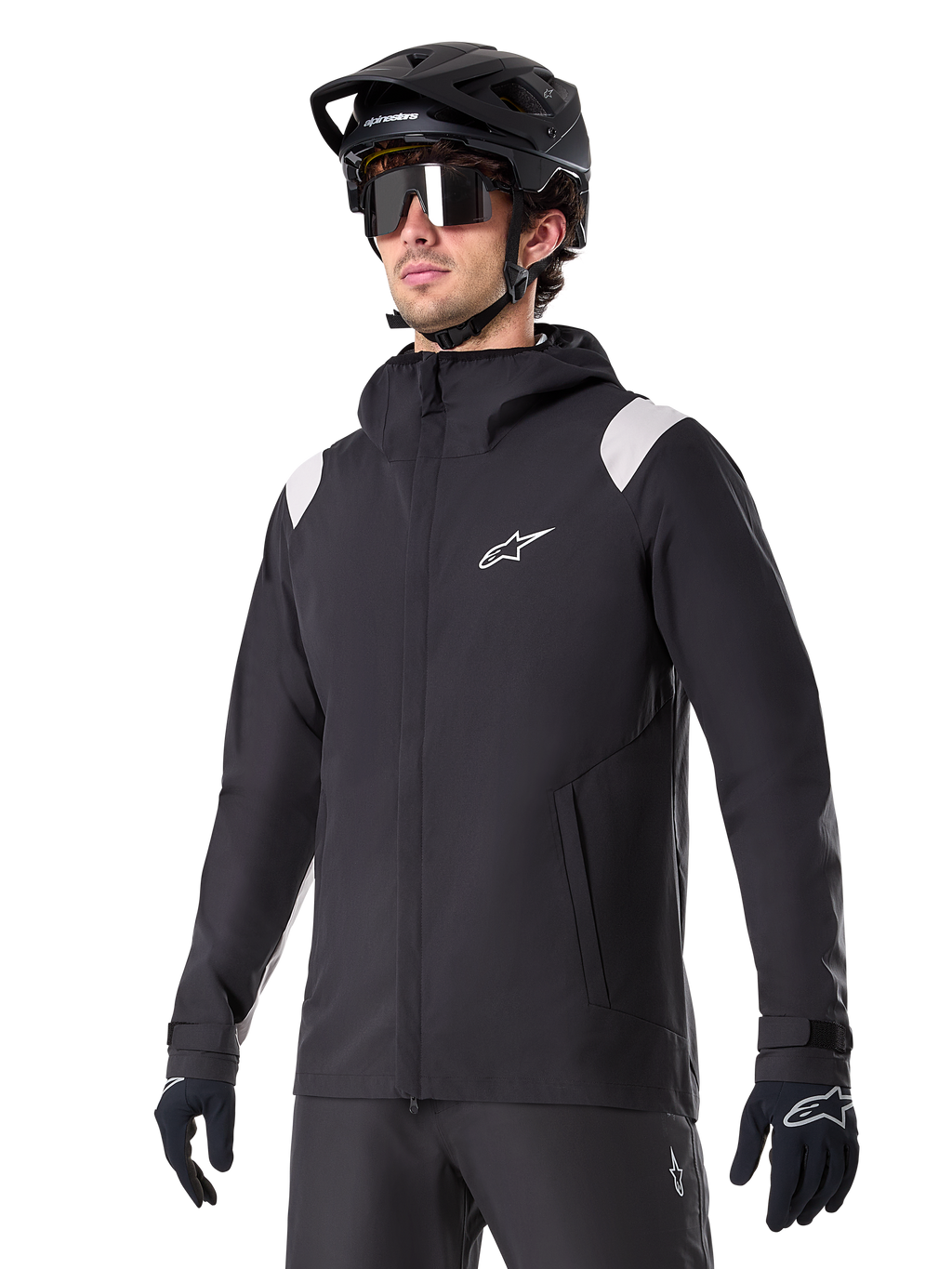 Alpinestars A-Dura Rain Jacket, MTB-regnjakke, sort med lysegrå skulderdetaljer, båret af en rytter med sort MTB-hjelm og solbriller, hvidt logo på brystet, vandtæt konstruktion, koordineret med sorte bukser og handsker til terrænkørsel