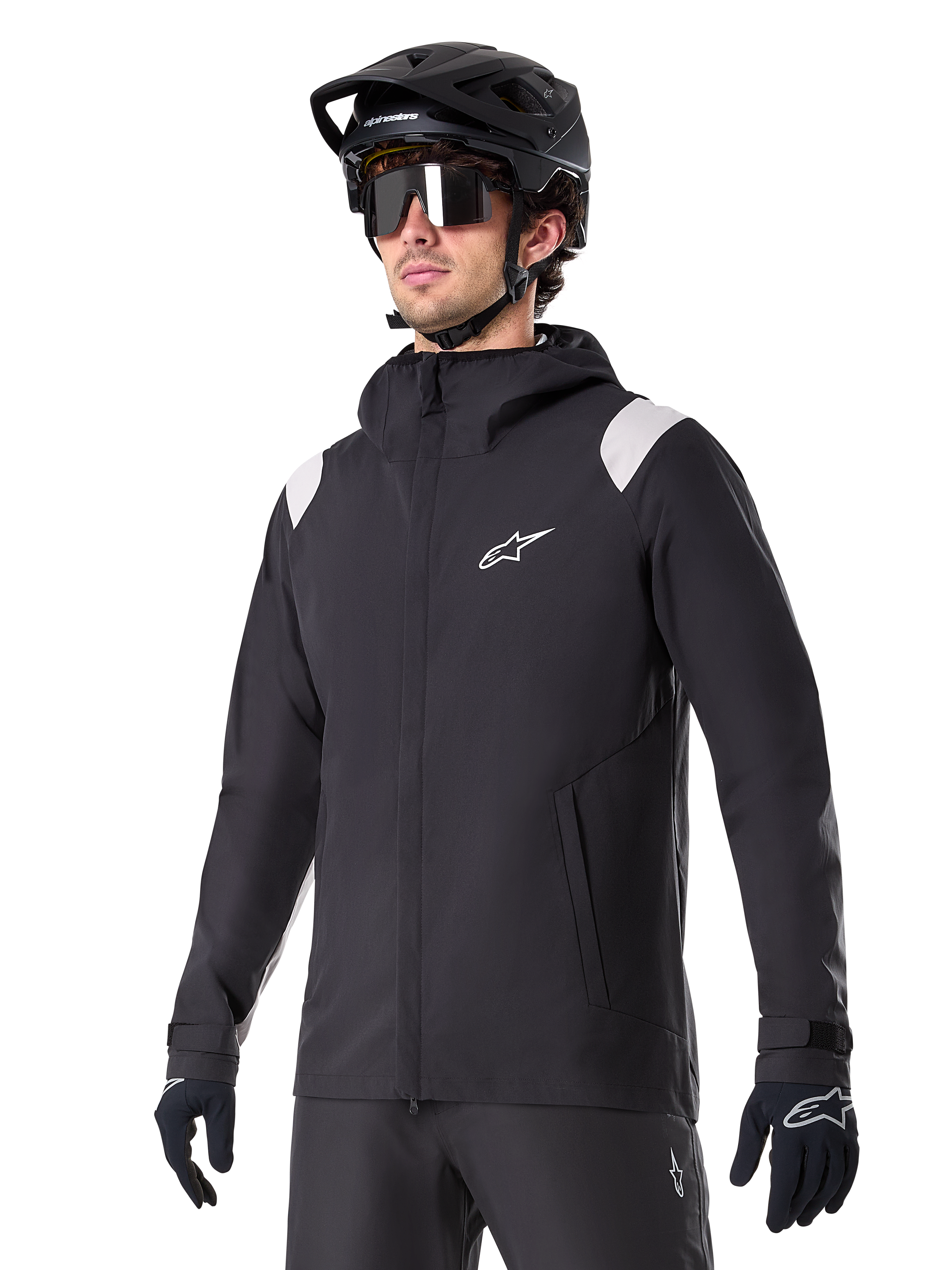 Alpinestars A-Dura Rain Jacket, Mountain Bike Rain Jacket, Black with light gray shoulder accents, worn by a rider with a black MTB helmet and sunglasses, white chest logo, waterproof construction, coordinated with black pants and gloves for off-road cycling