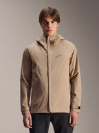 Alpinestars A-Dura Rain Jacket, lysebrun mountainbike-regnjakke med hætte, båret af en model, med lille logo på brystet, justerbare manchetter og skjult lynlås foran, vandtæt cykeludstyr
