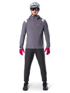 Alpinestars A-Dura Rain Jacket, Mountain Bike Jacket, Dark Titanium Gray with pink logo, worn with grey MTB helmet and bright pink gloves, protective 2.5-layer membrane design for wet weather cycling