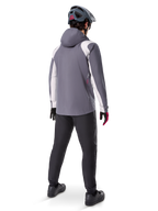 Alpinestars A-Dura Rain Jacket, Mountain Bike Jacket, Dark Titanium Gray with white panels, back view of rider wearing matching gray helmet and black pants, technical outdoor gear for wet weather