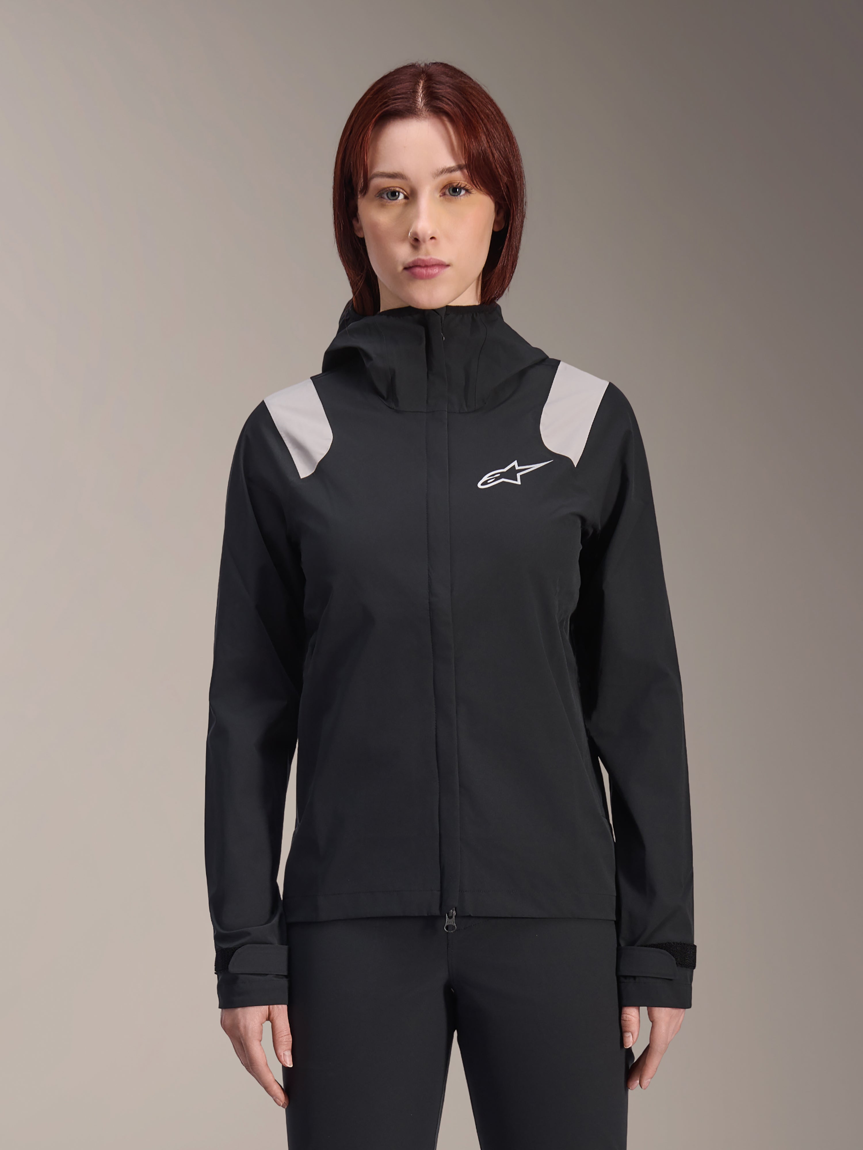 Alpinestars Stella A-Dura regnjakke, cykelregnjakke til damer, sort med lysegrå skulderpaneler, teknisk skaljakke med hætte og hvidt logo på brystet, justerbare velcromanchetter, professionelt udstyr til MTB og kørsel i vådt vejr