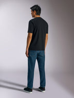 Alpinestars Ageless Shadow CSF Tee, kortærmet t-shirt, sort, set bagfra, båret med blå jeans og sorte sneakers, afslappet motorsport-inspireret streetwear