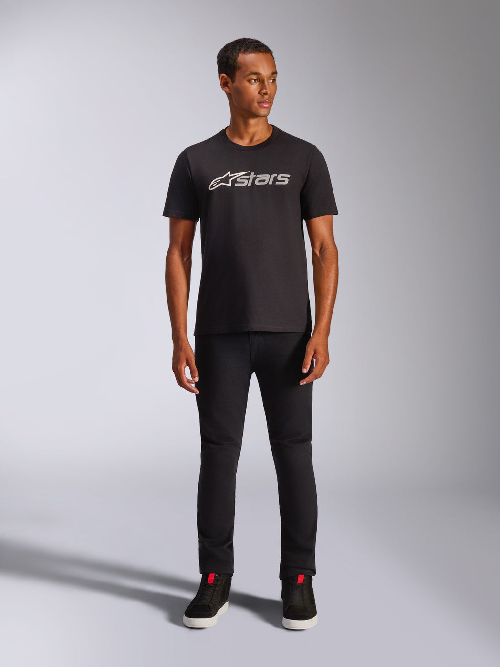 Alpinestars Blaze 2.0 CSF Tee, Short Sleeve T-Shirt, Black with Grey and White Front Logo, worn by model with black pants and black shoes, casual motorsport-inspired streetwear