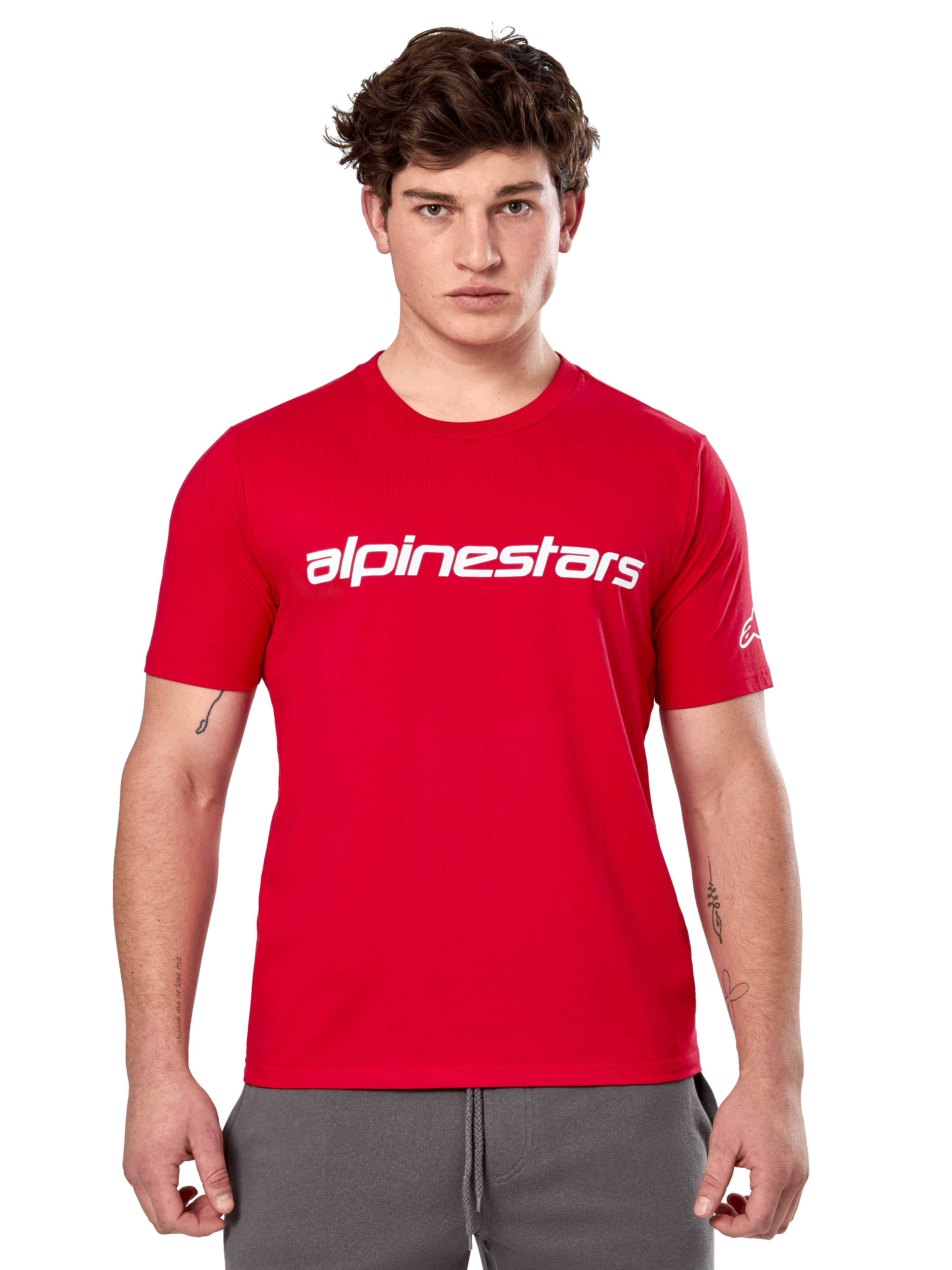 Alpinestars Linear Wordmark 2.0 CSF Tee, kortærmet rød T-shirt, hvidt lineært ordmærke på brystet og Ageless-logo på ærmet, båret af mandlig model med grå joggingbukser, casual motorsport-inspireret streetwear