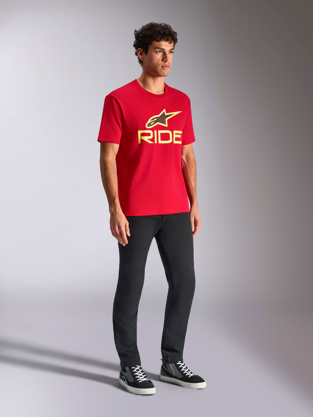 Alpinestars Ride 4.0 CSF Tee, kortærmet t-shirt, rød, gult og sort logo på fronten, båret med sorte bukser og sneakers, casual motorsport-streetwear