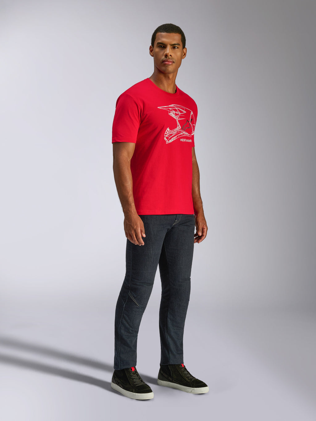 Alpinestars CSF Tee, kortærmet T-shirt, rød, hvid MX-hjelm-grafik, båret af model med mørke denimjeans og sorte sneakers, casual motorsport streetwear