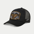 Alpinestars Heritage Patch Trucker-kasket, sort, kasket med struktureret krone og kurvet skygge, stor broderet heritage-patch på fronten med vinget hjul og teksten 'Racing Ahead Est. 1963', sorte mesh-paneler bagpå med stjernelogo på siden, casual motorsport-livsstilshovedbeklædning