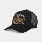 Alpinestars Heritage Patch Trucker-kasket, sort, kasket med struktureret krone og kurvet skygge, stor broderet heritage-patch på fronten med vinget hjul og teksten 'Racing Ahead Est. 1963', sorte mesh-paneler bagpå med stjernelogo på siden, casual motorsport-livsstilshovedbeklædning
