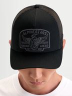 Alpinestars Heritage Patch Trucker Cap, sort og grå trucker cap med buet skygge, struktureret krone, twill-front og poly mesh-bagpanel med stort broderet logopatch, båret af person