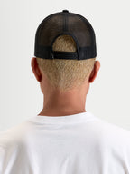 Alpinestars Heritage Patch Trucker cap, sort kasket, set bagfra der viser justerbar snapback-lukning og poly mesh-konstruktion, båret af model