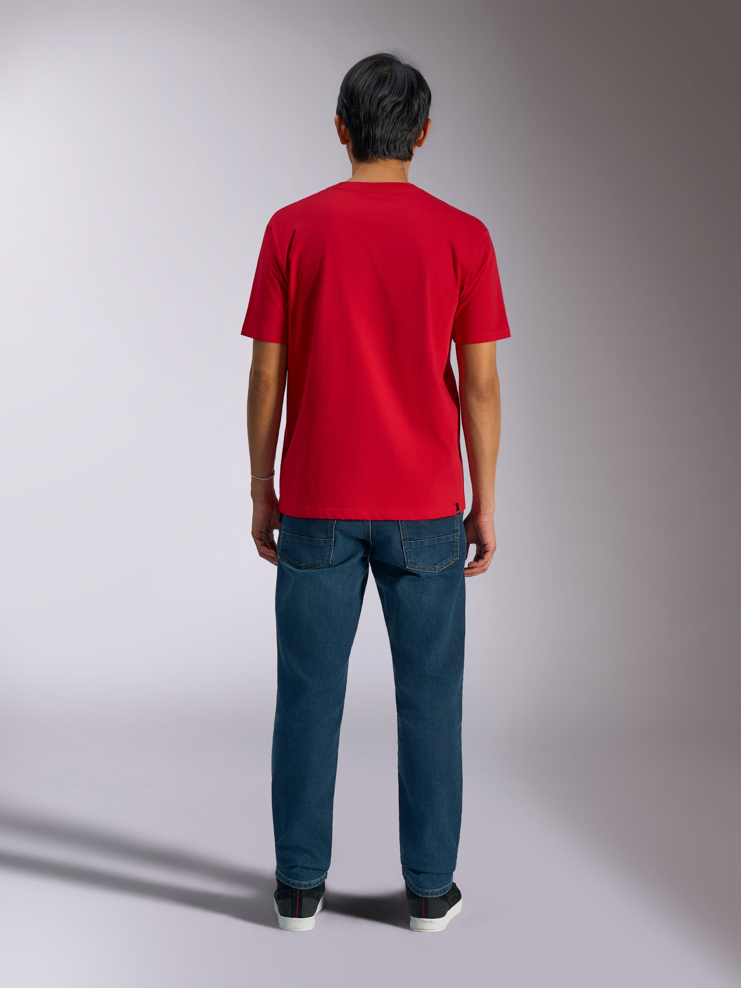 Alpinestars Ageless Shadow CSF Tee, rød kortærmet t-shirt set bagfra, båret med mørkeblå denimjeans og sorte sneakers, casual motorsport-streetwear