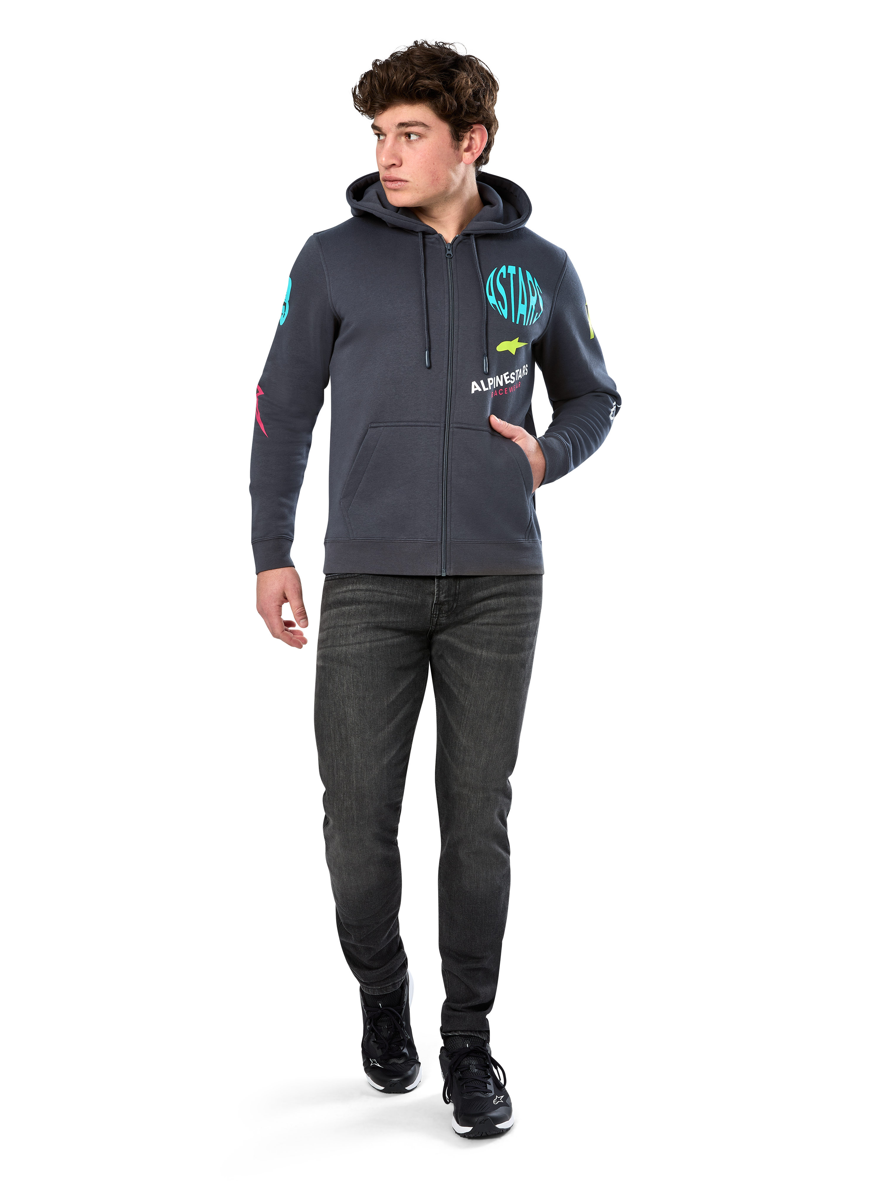 Alpinestars Variegate Hoodie, fleecehættetrøje med lynlås foran, Gunmetal grå, båret af model med sorte jeans og sneakers, med turkis 'ASTARS' branding og farverig logokunst på ærmer og bryst, afslappet motorsport-inspireret streetwear