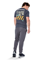 Alpinestars No Barrier CSF Tee, kortærmet t-shirt, koksgrå, set bagfra med stor distressed fotografik med gule diagonale striber og hvidt logo, afslappet motorsport-inspireret streetwear