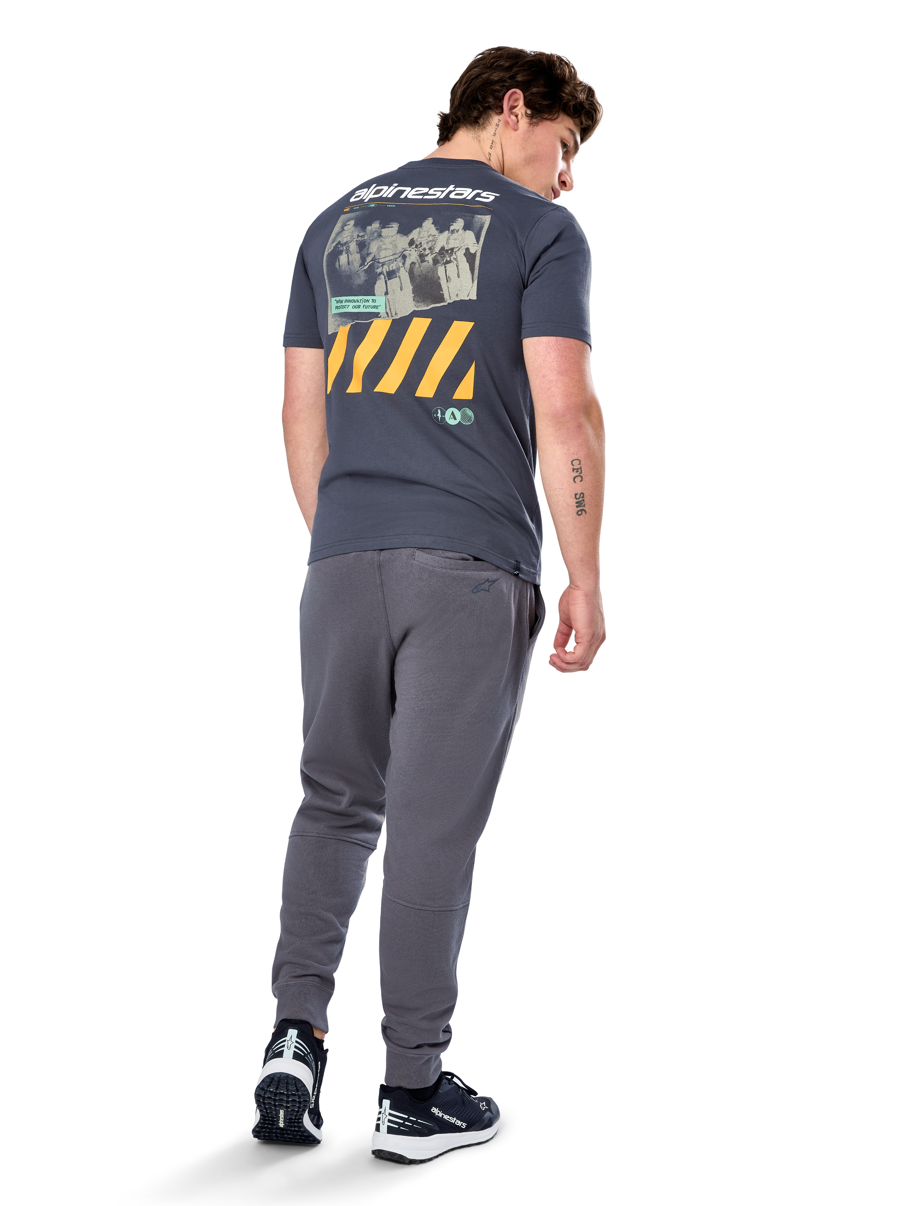 Alpinestars No Barrier CSF Tee, kortærmet t-shirt, koksgrå, set bagfra med stor distressed fotografik med gule diagonale striber og hvidt logo, afslappet motorsport-inspireret streetwear