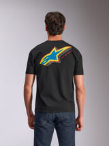 Alpinestars Angler CSF Tee, kortærmet t-shirt, sort, set bagfra viser et livligt flerfarvet Astars-logo med perforeret fyld og 'RACING AHEAD'-tekst, båret med blå jeans, afslappet motorsport-inspireret beklædning