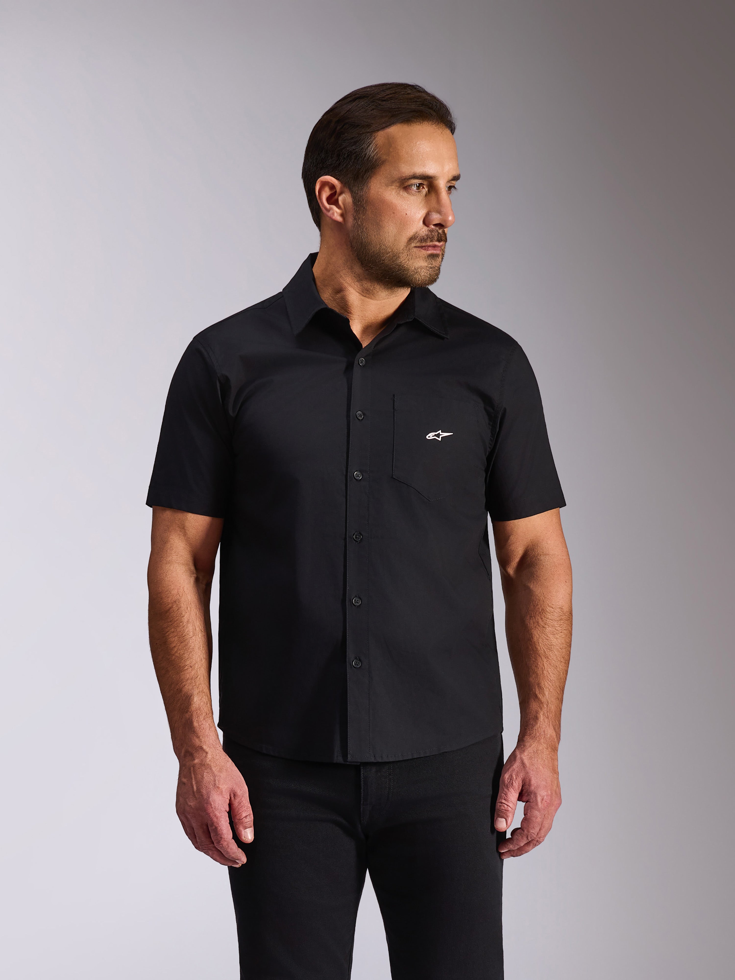Alpinestars Strive Woven skjorte, kortærmet skjorte med knapper, sort, hvidt Alpinestars-logo på brystlommen, afslappet motorsport streetwear