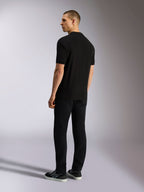 Alpinestars Endeavor Classic Polo, Short Sleeve Pique Polo Shirt, Black, back view of male model wearing black pants and sneakers, casual motorsport-inspired streetwear