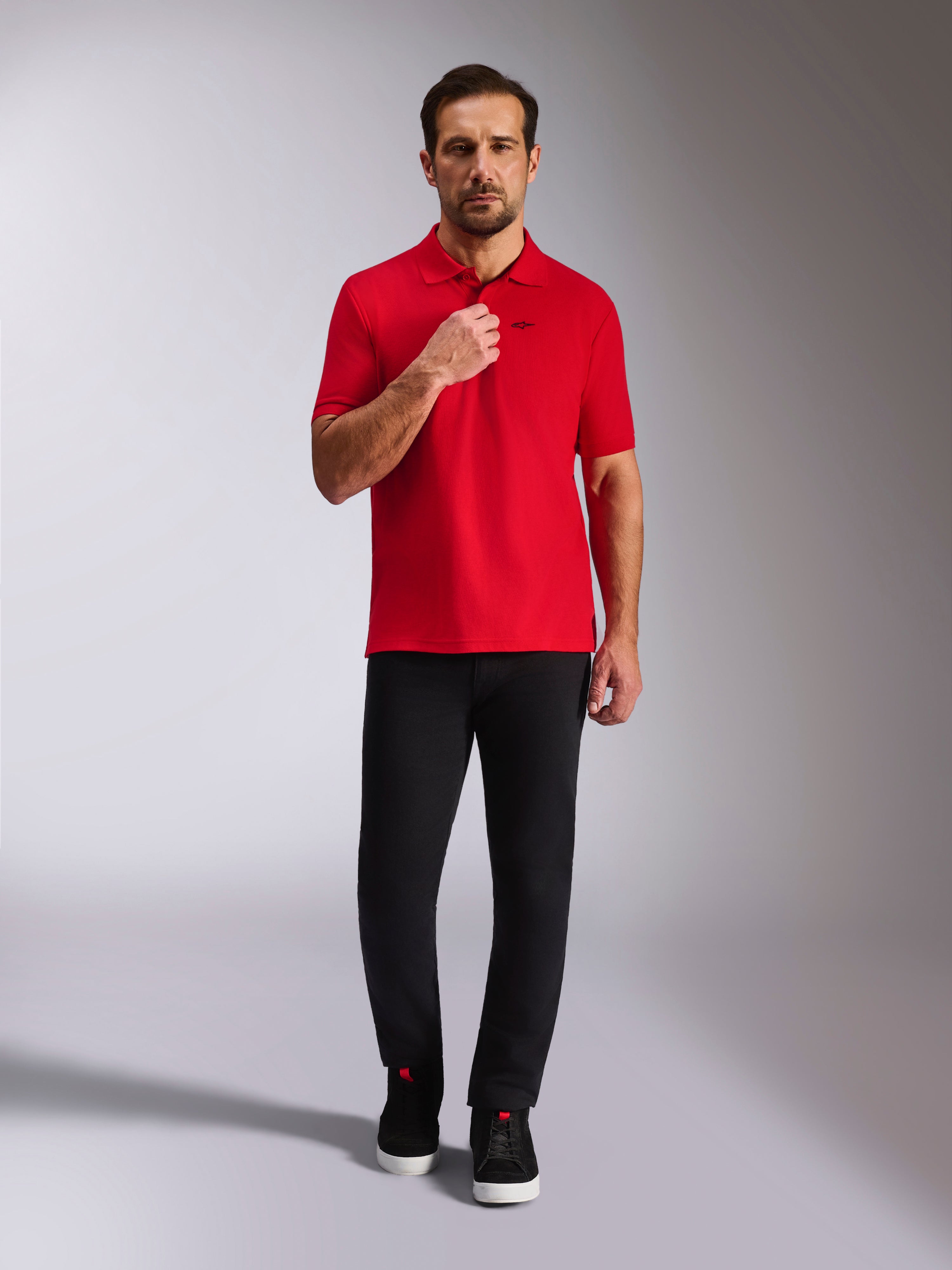 Alpinestars Endeavor Classic Polo, rød piqué-poloshirt, kortærmet med sort Astars-logo, ribkrave og ribkanter på ærmerne, båret med sorte bukser og sneakers, afslappet motorsport-inspireret streetwear