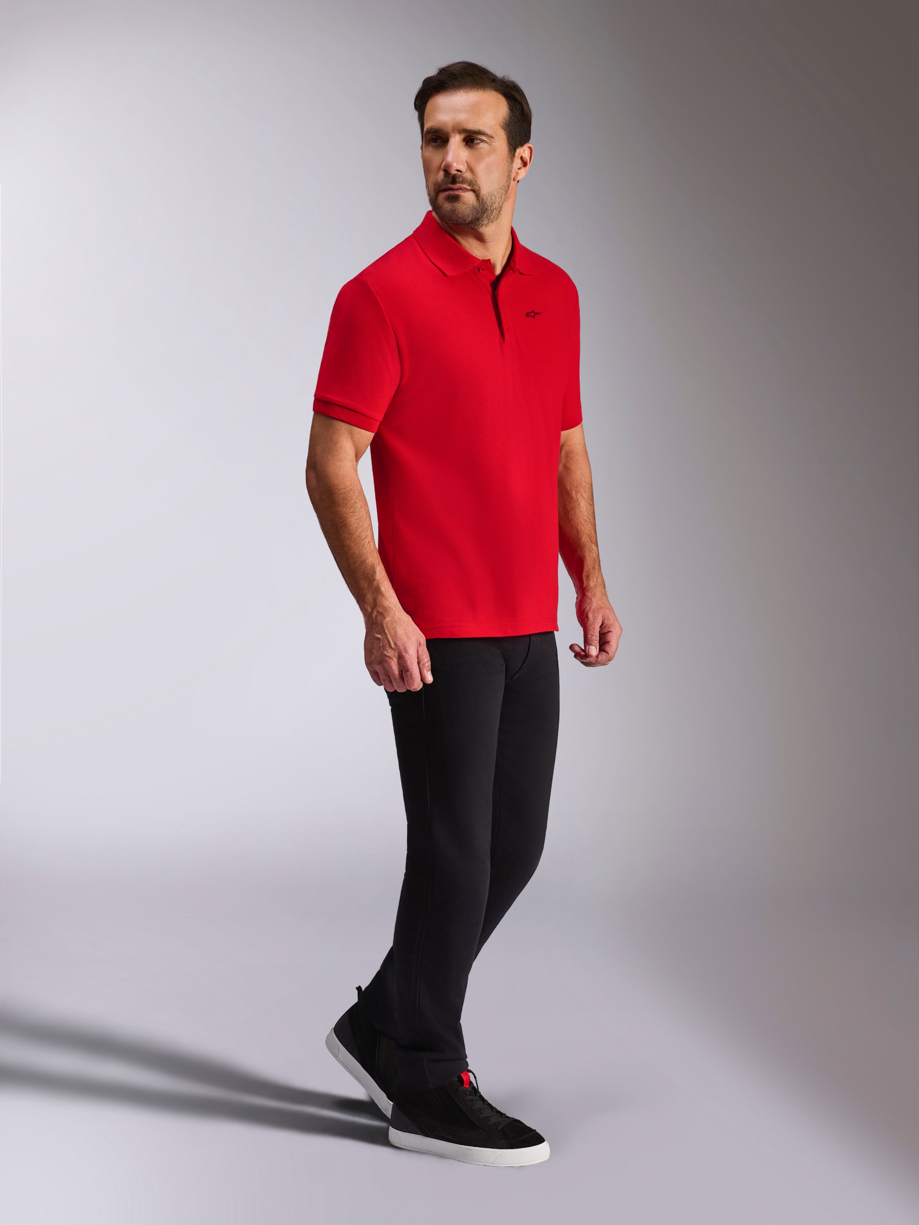 Alpinestars Endeavor Classic Polo, rød kortærmet piqué-polo, lille sort Astars-logo, ribkrave og ribkanter, båret af en model med sorte bukser og sneakers, afslappet motorsport-inspireret streetwear