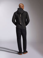 Alpinestars Insight Hoodie, sort, set bagfra på model, med et lodret hvidt stribelogo på ryggen med teksten "Racing Ahead", afslappet sportstøj-hættetrøje i tri-blend dobbeltlags fleece, kombineret med sorte bukser.