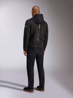 Alpinestars Insight Hættetrøje, sort sportshættetrøje, set bagfra med en lodret hvid stribe med 'RACING AHEAD' branding, logo på ærmet, kombineret med sorte bukser og sneakers, afslappet motorsport-inspireret design