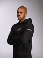 Alpinestars Insight Hoodie, afslappet sportstøj-hættetrøje, sort, hvidt Astars-logo på brystet og tekstlogo på overarmen, model iført hættetrøje med armene over kors, førsteklasses dobbeltsidet fleece-konstruktion