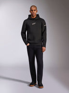 Alpinestars Insight hættetrøje, sort pullover-hættetrøje med hvidt Astars-logo på brystet og ærmet, båret af en model med sorte bukser og sorte sneakers, afslappet motorsport-inspireret streetwear