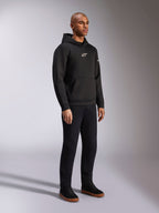 Alpinestars Insight Hættetrøje, sort, afslappet pullover-fleecehættetrøje med hvidt Astars-logo på brystet, kængurulomme, kombineret med sorte bukser og sneakers, studiebillede i fuld figur, motorsport-inspireret streetwear